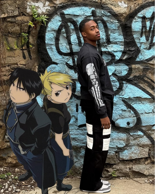 Shaquan Parson standing next to two fullmetal alchemist characters against a graffiti-covered wall wearing kayoz naruto shinobi cargos and fullmetal alchemist sweater